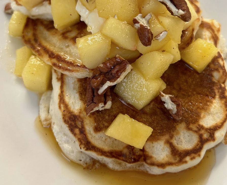 A plate of pancakes topped with apples.