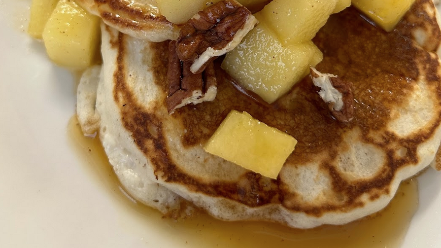 A plate of pancakes topped with apples.