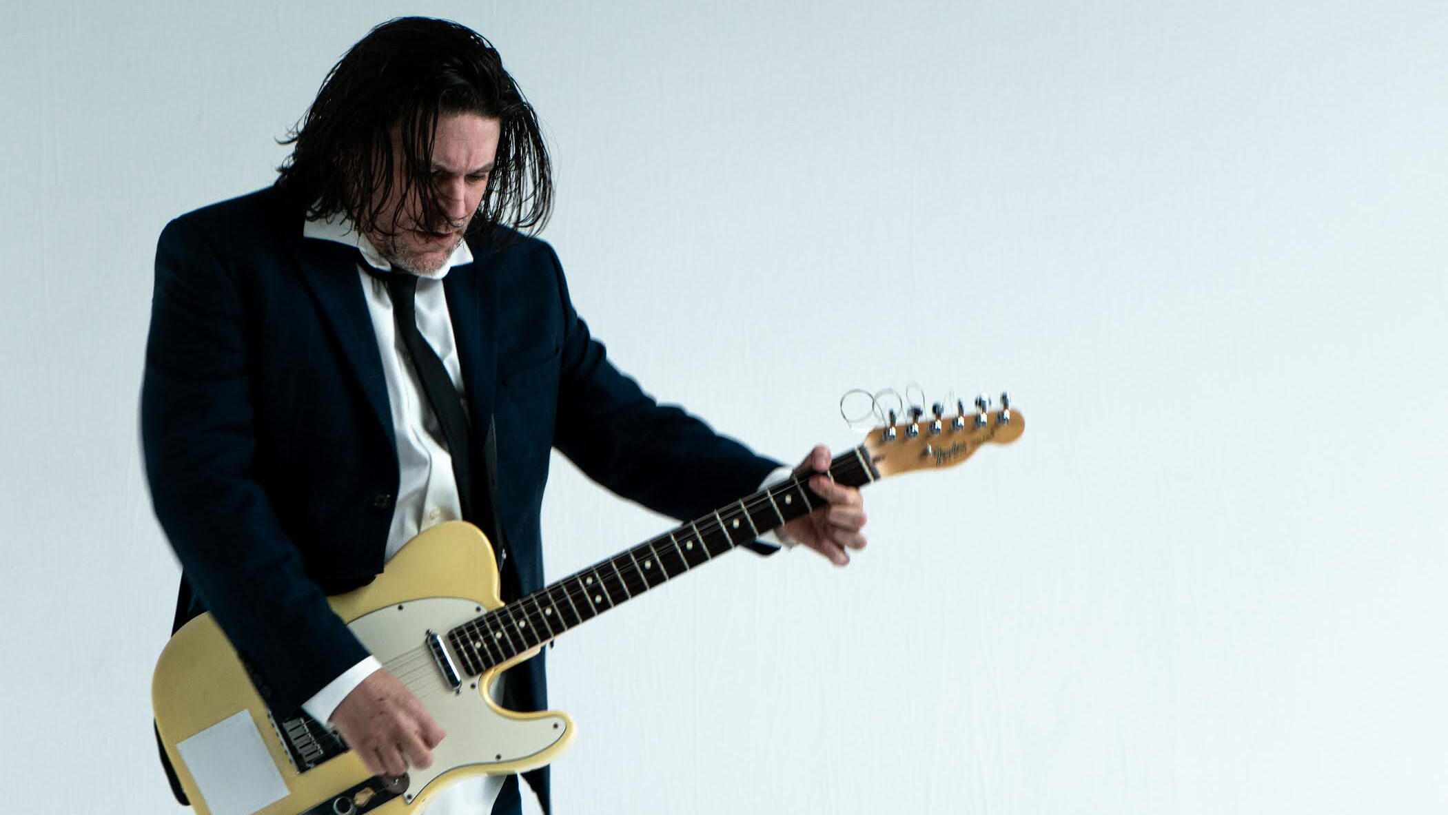 Musician Andras Jones holding a white guitar.